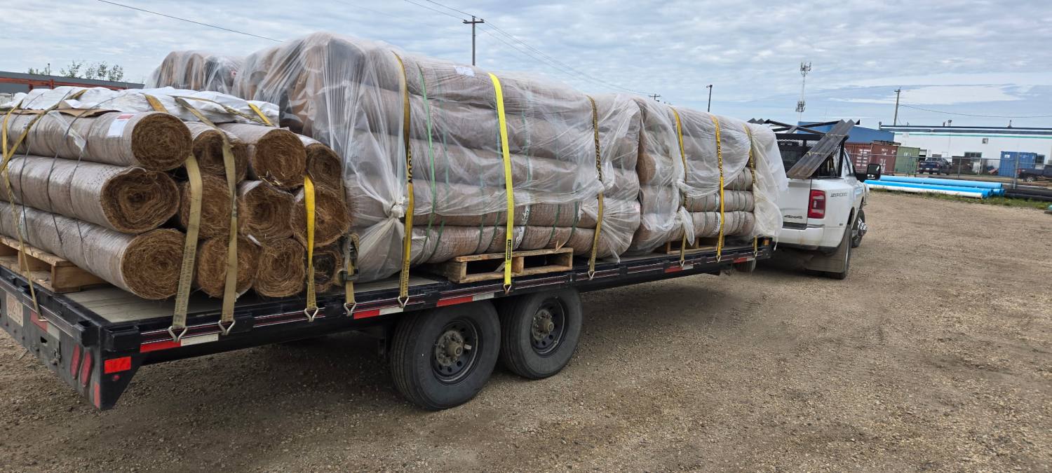 A loaded RCT deck trailer behind a one-ton dually, freight strapped down.